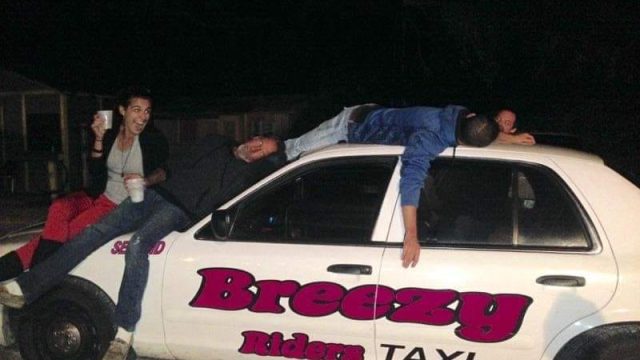 A group of people sitting on top of a taxi.