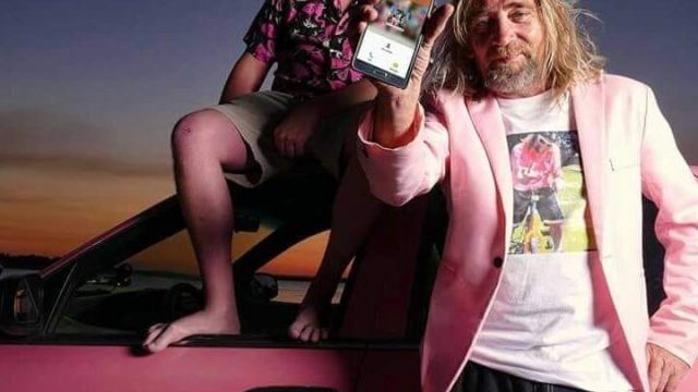 Two men in pink standing next to a pink car.