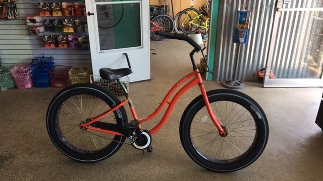 An orange bike is parked in a garage.